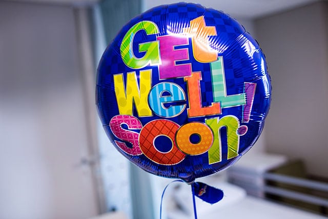 Iemand beterschap wensen, hier knapt iedereen van op! 2 Blauwe folieballon met kleurrijke letters Get Well Soon in ziekenhuisomgeving