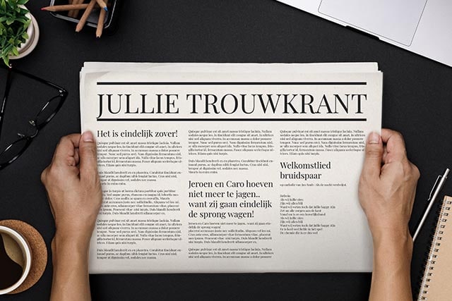 Persoon leest trouwkrant met artikelen over een bruiloft, naast koffie, bril, potloden en laptop.