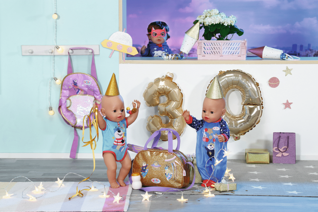 Twee poppen met feesthoedjes voor gouden 30-ballonnen en feestdecoraties binnen.