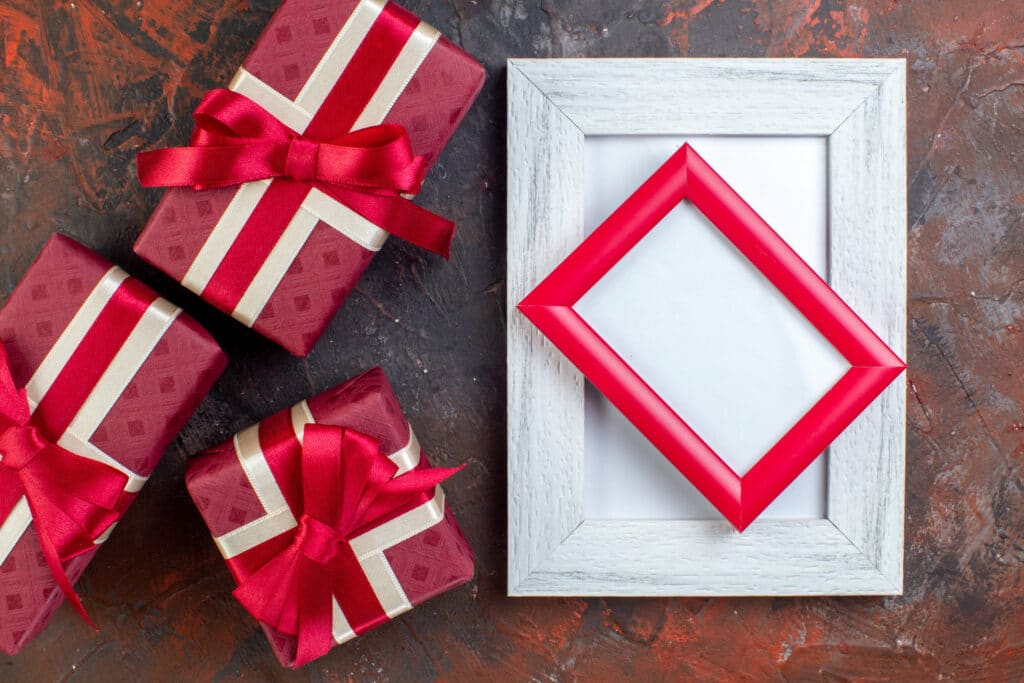 Rode cadeaudozen met strik naast een lege fotolijst
