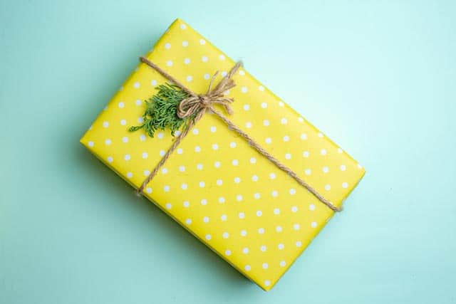 De leukste cadeaus voor als je geen speelgoed wilt geven! 2 Geel cadeau met witte stippen, gebonden met touw en versierd met groen dennentakje.