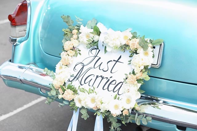 De leukste gezamenlijke cadeaus voor het bruidspaar! 1 Lichtblauwe vintage auto met bloemrijke "Just Married" bord aan de achterbumper.