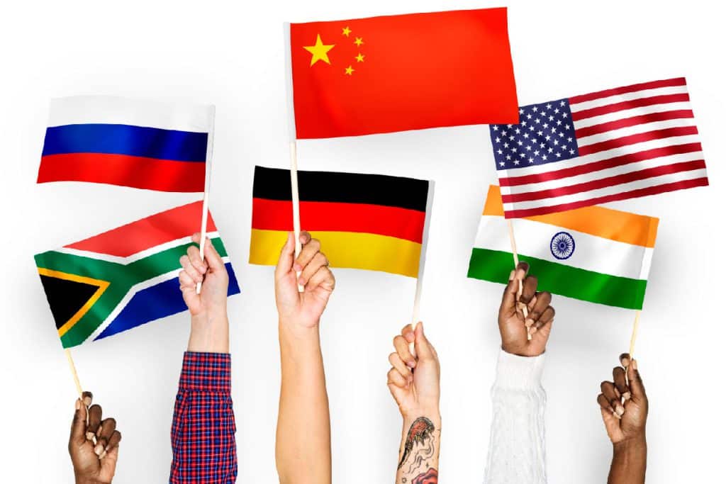 Handen houden kleine vlaggen vast van Rusland, Zuid-Afrika, China, Duitsland, Verenigde Staten en India.