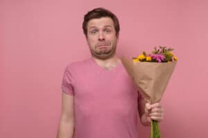 Man met bloemen in de hand als sorry cadeau