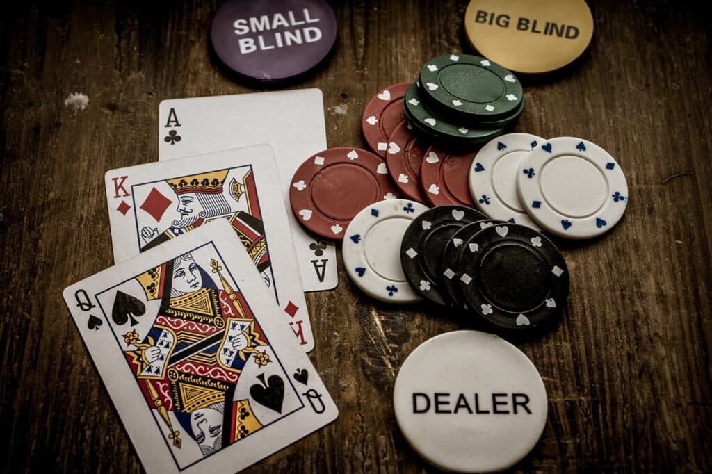 Pokerspel met speelkaarten, fiches en dealer-, small blind- en big blind-aanduidingen op hout.