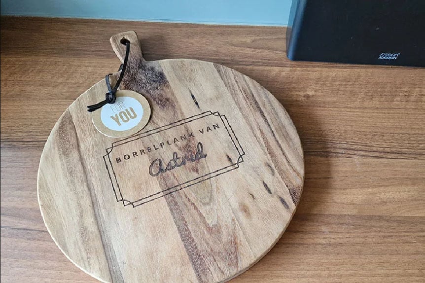 Ronde houten borrelplank met handvat en label, gegraveerd met BORRELPLANK VAN Astrid.