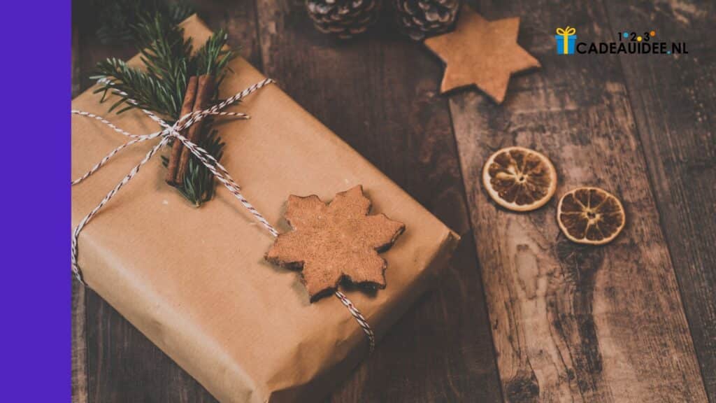 Met bruin papier ingepakt cadeau met dennengroen, kaneelstokjes, houten sneeuwvlok en gedroogde sinaasappel.